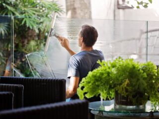 man-in-gray-shirt-cleaning-clear-glass-wall-near-sofa-713297-scaled-1